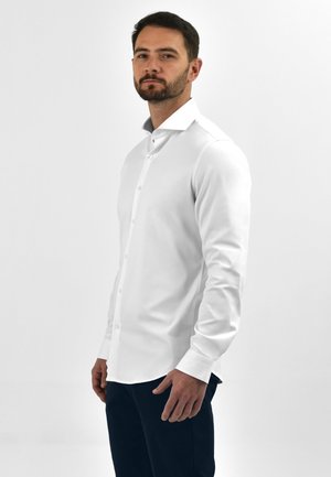 Witte button-up shirt met een klassieke kraag en lange mouwen, met een gladde textuur en slim fit, gecombineerd met donkere broek.