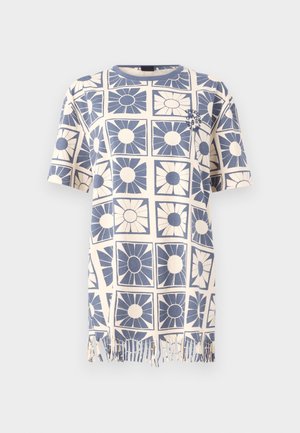 T-shirt à manches courtes en coton avec un motif floral bleu et crème, présentant des franges au niveau de l'ourlet. Coupe droite et col rond.