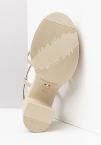 Suola di scarpa beige con tacco alto, caratterizzata da un motivo di presa testurizzato, con marchio "NeroGiardini", taglia 37 e un design slanciato.