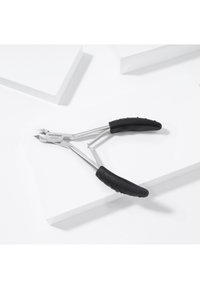 Nail cuticle nipper with stainless steel blades and black textured grip handles resting on white geometric surfaces.
