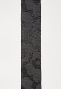 Black fabric strap with textured floral pattern, featuring a woven design. Smooth surface with raised accents for added detail.