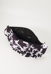 Borsa a spalla con motivo bianco e nero, realizzata in tessuto, con una texture liscia, chiusura con zip e una tasca interna con etichetta.