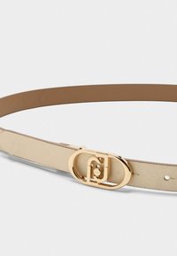 Cintura testurizzata color tan e crema con una fibbia ovale dorata e un logo distintivo. Il materiale è liscio con una finitura a motivi.