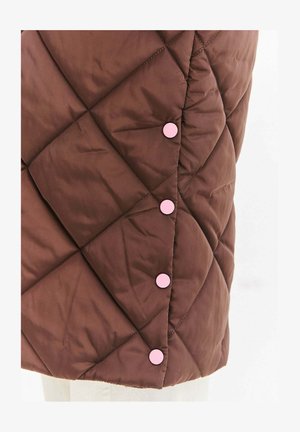 Brązowa pikowana tkanina z ukośnym przeszyciem i czterema równomiernie rozmieszczonymi okrągłymi różowymi zatrzaskami wzdłuż szwu.