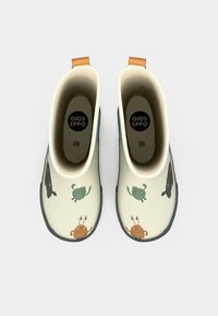Une paire de bottes de pluie pour enfants couleur crème avec des poignées brunes, décorées d'animaux de dessin animé ludiques, vues de dessus.
