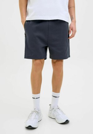 Shorts de sport navy avec une taille élastique, des poches latérales et une coupe décontractée, associés à des chaussettes de sport blanches et des baskets.