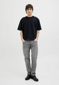 Svart oversized t-shirt, grå raka jeans och svarta skor. Bekväm tyg; utan mönster. Lätt design med avslappnad passform.