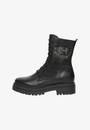 Botte de combat en cuir noir à lacets avec une semelle épaisse et une sangle décorative en métal sur le côté.