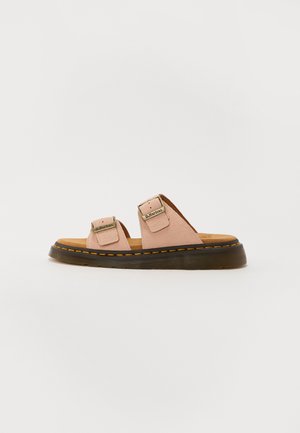 Light pink leather sandals with two adjustable straps, black rubber sole, and contrasting yellow stitching. Flat design and textured footbed.