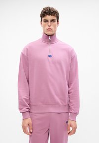Roza zip-majica z dolgimi rokavi, izdelana iz mehkega blaga, z logotipno oznako na prsih ter rebrastimi manšetami in robom.
