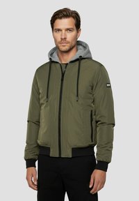 Olivgrüne Bomberjacke mit grauer Kapuze, Reißverschluss vorne, elastischen Bündchen und Seitentaschen; glatte Textur und schlankes Design.