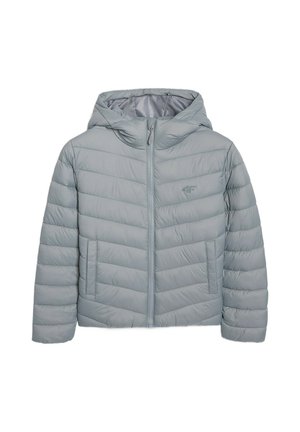 Jonge jongen staat naar voren gericht, draagt een lichtblauw pufferjack, donkergrijs shirt, lichtgrijze joggingbroek en grijze sneakers. Neutrale achtergrond.