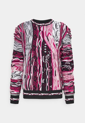 Suéter de punto multicolor con patrones abstractos en rosa, negro y blanco, mangas largas, puños acanalados y escote redondo sobre fondo liso.