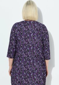Abito a maniche corte con un motivo geometrico viola e nero, dal fit morbido. Realizzato in tessuto leggero con una texture liscia.