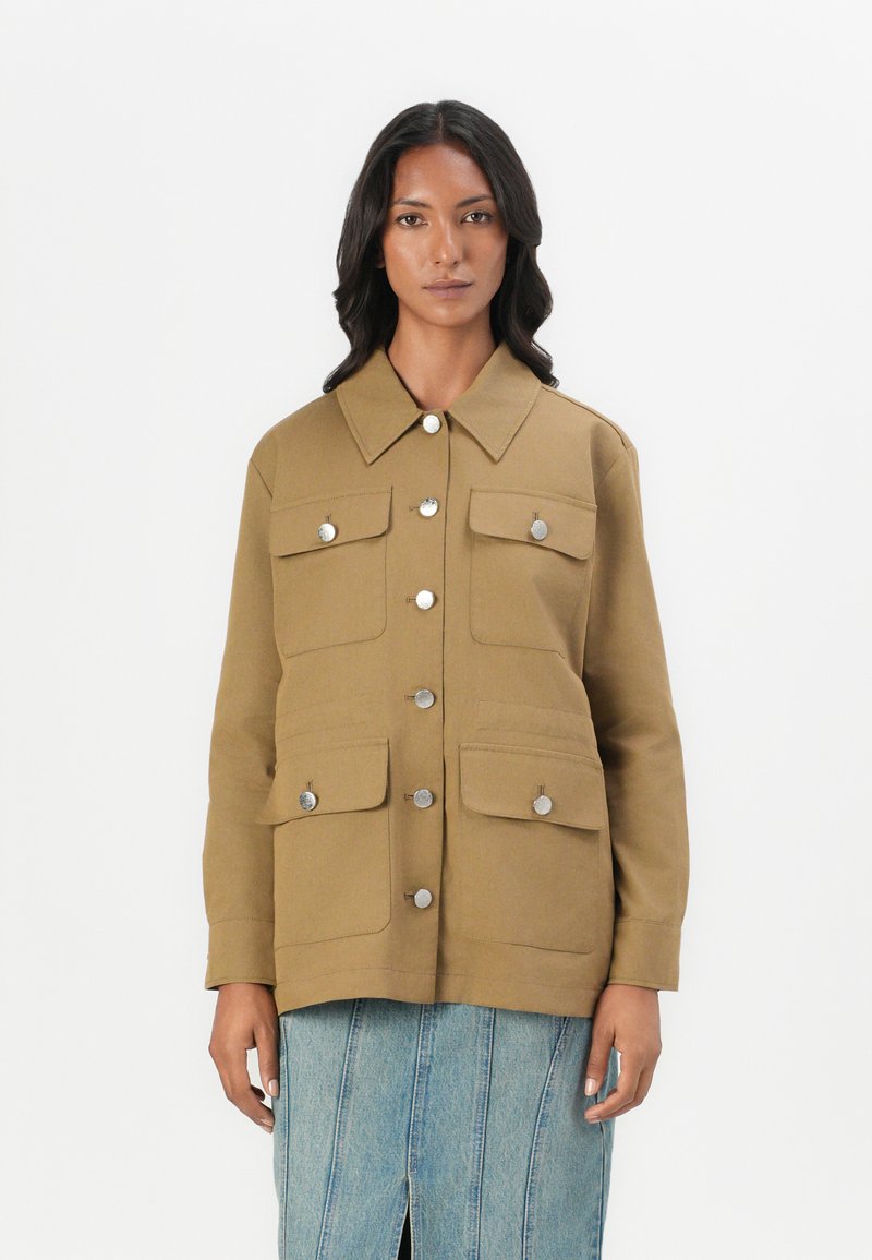 Giacca utility khaki con chiusure a bottone argentate, quattro tasche frontali e colletto classico. Realizzata in tessuto resistente, taglio aderente.