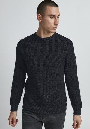 Dark gray knit sweater with a textured pattern, crew neckline, long sleeves, and a small logo detail on the left sleeve.