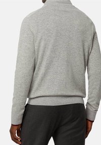 Maglione grigio a maglia con colletto alto e polsini a coste. Presenta un tessuto testurizzato e una vita aderente. Dettagli di cucitura visibili.