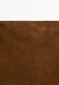 Braunes Wildlederstoff mit sichtbaren Nähten entlang der oberen Kante vor weißem Hintergrund.