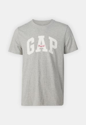 Pelēks kokvilnas t-krekls ar apaļu kaklu, īsām piedurknēm un lielu baltu "GAP" logo ar sarkanu "Original" tekstu.