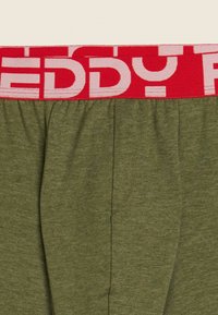 Boxer verde oliva con una fascia elastica rossa contrassegnata da testo bianco. Il tessuto sembra morbido, con una consistenza liscia e vestibilità comoda.