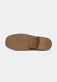 Semelle de chaussure noire avec une surface texturée ; semelle extérieure en caoutchouc marron avec une base plate et large et un détail en découpe rectangulaire.
