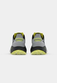 Γκρι αθλητικά παπούτσια με μαύρες σόλες και φωτεινές κίτρινες λεπτομέρειες. Δικτυωτό πάνω μέρος με υφή, σχεδιασμένο για στήριξη και πρόσφυση.