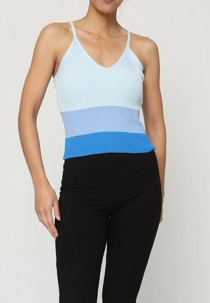 Débardeur côtelé avec un dégradé de bleu clair, bleu moyen et bleu foncé, doté de fines bretelles ajustables. Associé à un pantalon noir.