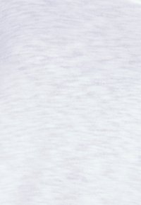Bílá bavlněná látka se měkkým, texturovaným povrchem. Jemné variace v barvě vytvářejí heathered efekt po celé ploše materiálu.