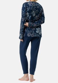 Laadun lahjakkuuden kankaasta valmistettu tummansininen kukkakuosiset pitkähihainen paita pyöreällä kaula-aukolla, yhdistettynä vastaaviin tummansinisiiin kapeisiin housuihin. Puuvillasekoitteesta, pehmeä rakenne, rento istuvuus.