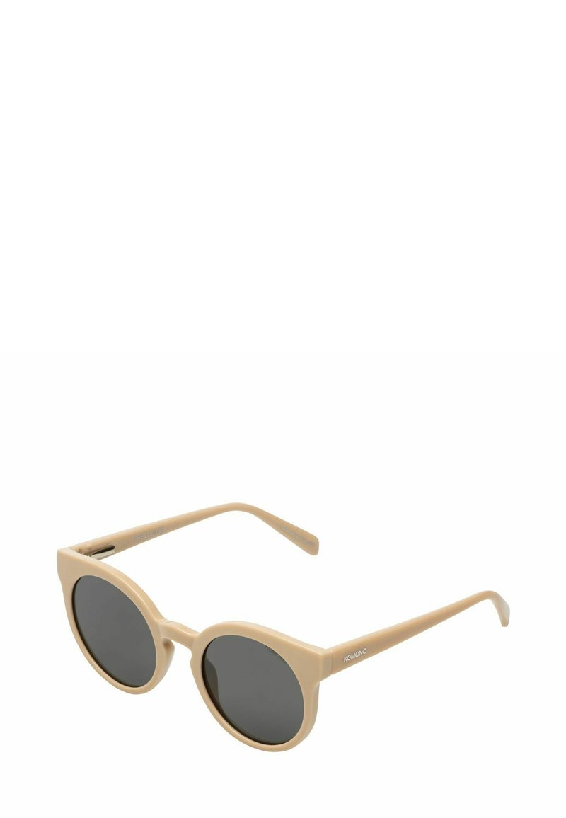 Lunettes de soleil en acétate beige avec des montures rondes et des verres foncés. Présentent des branches fines avec un logo d'un côté. Texture lisse sur l'ensemble.