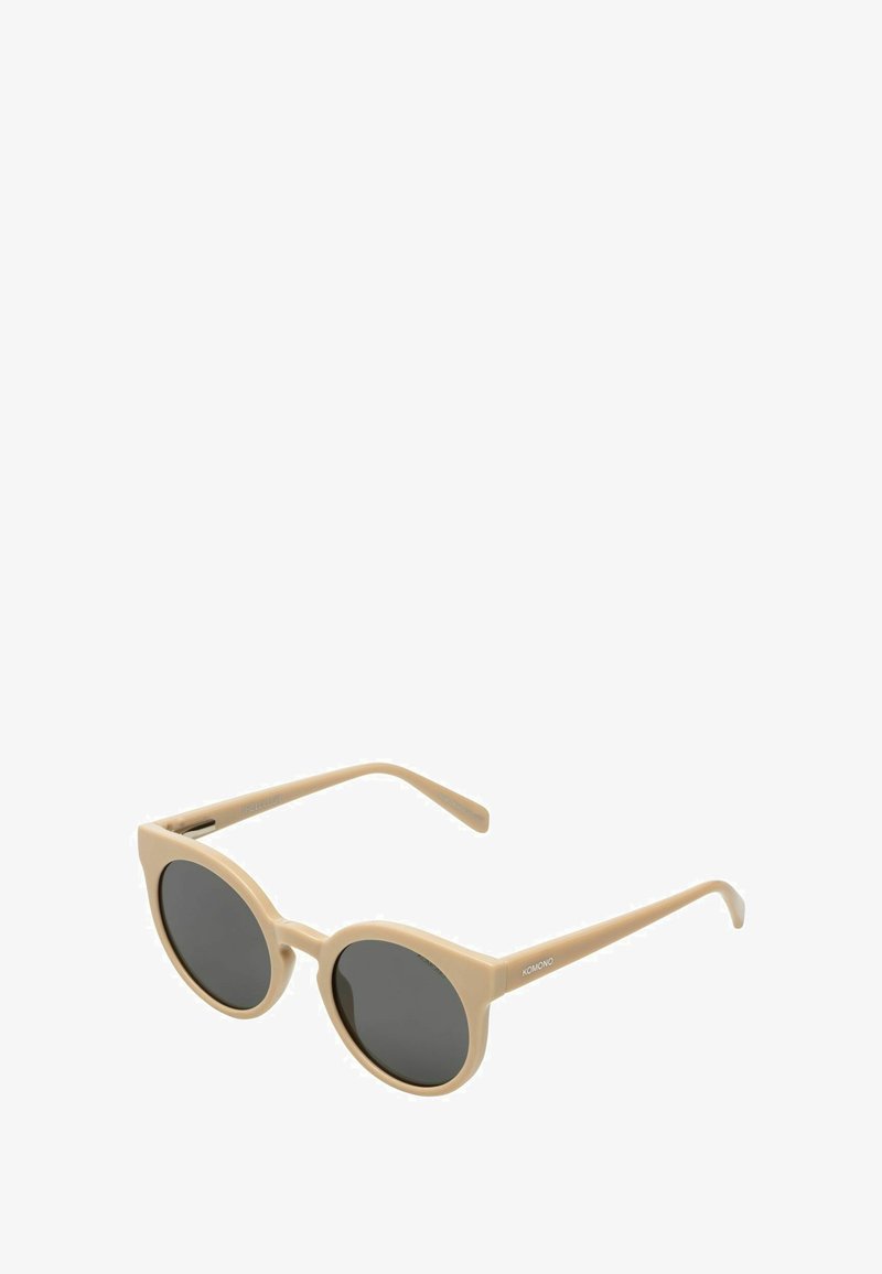 Lunettes de soleil en acétate beige avec des montures rondes et des verres foncés. Présentent des branches fines avec un logo d'un côté. Texture lisse sur l'ensemble.