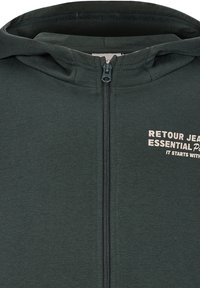 Dunkelgrüne Kapuzenjacke mit weicher Textur, ausgestattet mit einem Frontreißverschluss und bedrucktem Text auf der linken Brust in Beige.
