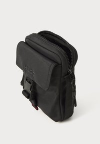 Borse a tracolla nera in nylon con scomparto principale con zip, tasca anteriore a patta e tracolla regolabile con fibbia. Le dimensioni sono circa 20 cm x 12 cm.