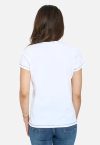 Camiseta blanca de manga corta con cuello redondo, con costuras azules en las mangas y el bajo, hecha de una tela suave y lisa.