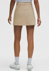 Beige knielange rok met een aansluitend ontwerp, gemaakt van een gladde stof. Voorzien van achterzakken en een tailleband met riemlussen.