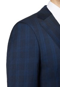 Granatowa marynarka w kratę z cienkimi niebieskimi paskami, z wyraźnymi ramionami i klapami w kształcie notcha.