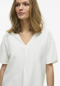 Weißes Baumwoll-T-Shirt mit V-Ausschnitt, kurzen Ärmeln, lockerer Passform und feiner Struktur. Mit einer zentralen Nahtdetails.