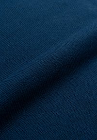 Tessuto lavorato a maglia blu navy con un motivo a coste testurizzato. Il materiale appare morbido e flessibile, con pieghe delicate che creano linee drappeggiate.