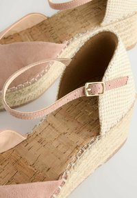 Roza suede in tkan krožnik z vrezanimi espadrilami in pluto podplatom. Ima trak z zlatim sponko in teksturirano podrobnost na tkanem zgornjem delu.