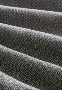 Tessuto piegato di un grigio scuro con una fine trama testurizzata, creando morbide gronde diagonali sotto una luce diffusa.