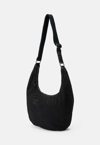 Schwarze, mondförmige Schultertasche aus Stoff mit einem langen, verstellbaren Riemen und einem sichtbaren Reißverschluss oben.