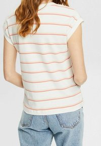 Witte short-sleeve shirt met roze strepen, ronde halslijn en opgerolde mouwen; gecombineerd met lichtblauwe denim jeans.