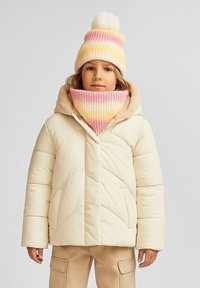 Beige dunjakke med hætte, prydet med lodret syning. Kombineret med en gradient strikhue og matchende tørklæde i pink og gule nuancer.