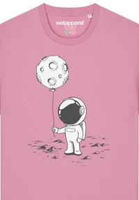 Roze katoenen T-shirt met een zwart-wit illustratie van een astronaut die een ballon vasthoudt in de vorm van een maan, met zichtbare oppervlakdetails.