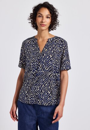 Haut à motifs navy et beige avec des manches courtes, un col en V et un design géométrique dans différentes nuances de bleu et de crème.