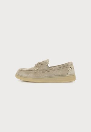 Mocassin en daim marron clair avec semelle beige, détails cousus et coutures style mocassin, présenté de profil sur fond blanc.