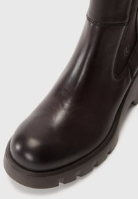 Brown leather ankle boot with a rounded toe, smooth texture, chunky rubber sole, and side elastic panels for easy wear.