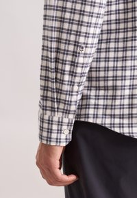 Camicia in cotone a quadri bianca e blu navy con polsini con bottoni, dotata di un piccolo logo ricamato vicino all'orlo e una vestibilità comoda.