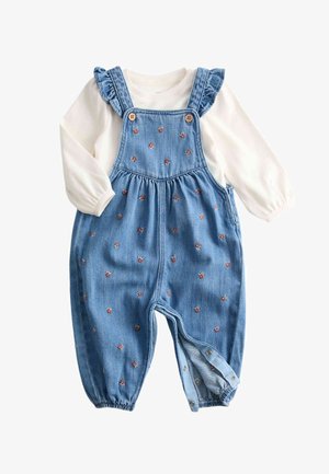 Hvid skjorte med lange ærmer kombineret med blå denim-ungerer med små blomsterbroderier og knapper på stropperne og manchetterne.