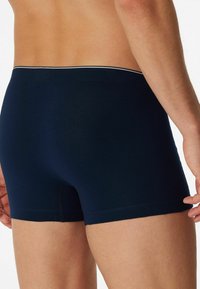 Navy blue boxer briefs with a snug fit, featuring a contrasting waistband. Made from soft, smooth fabric with minimal stitching details.